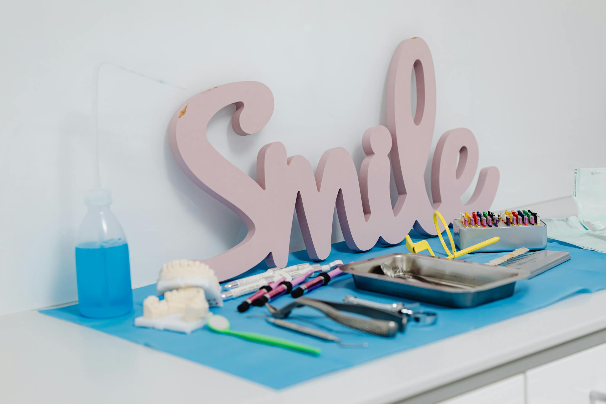 Collection of dental instruments on clinic desk, featuring a 'Smile' decor piece, promoting oral care and hygiene.