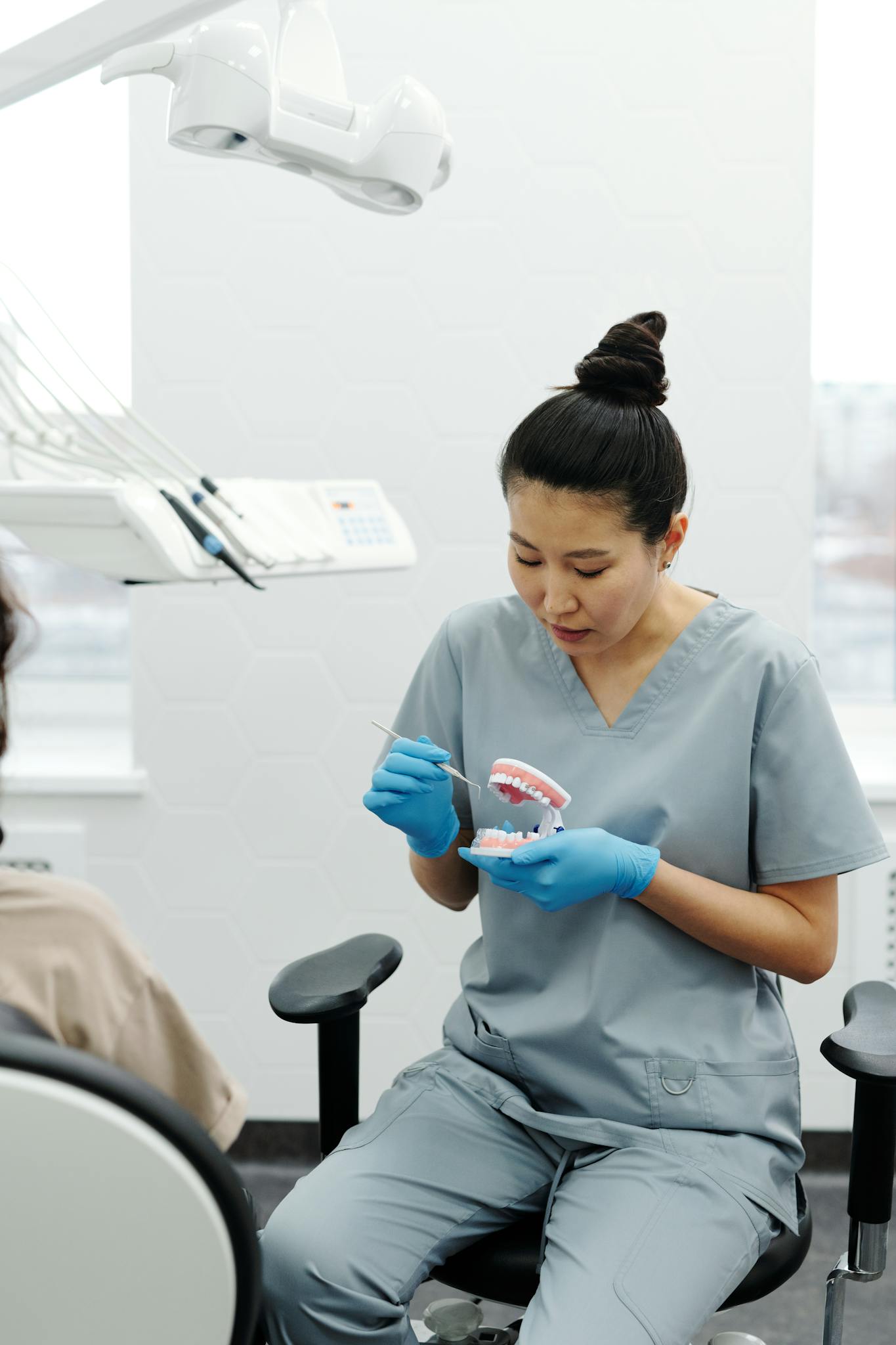 Professional dentist instructs a patient on dental care using a denture model in a modern clinic.