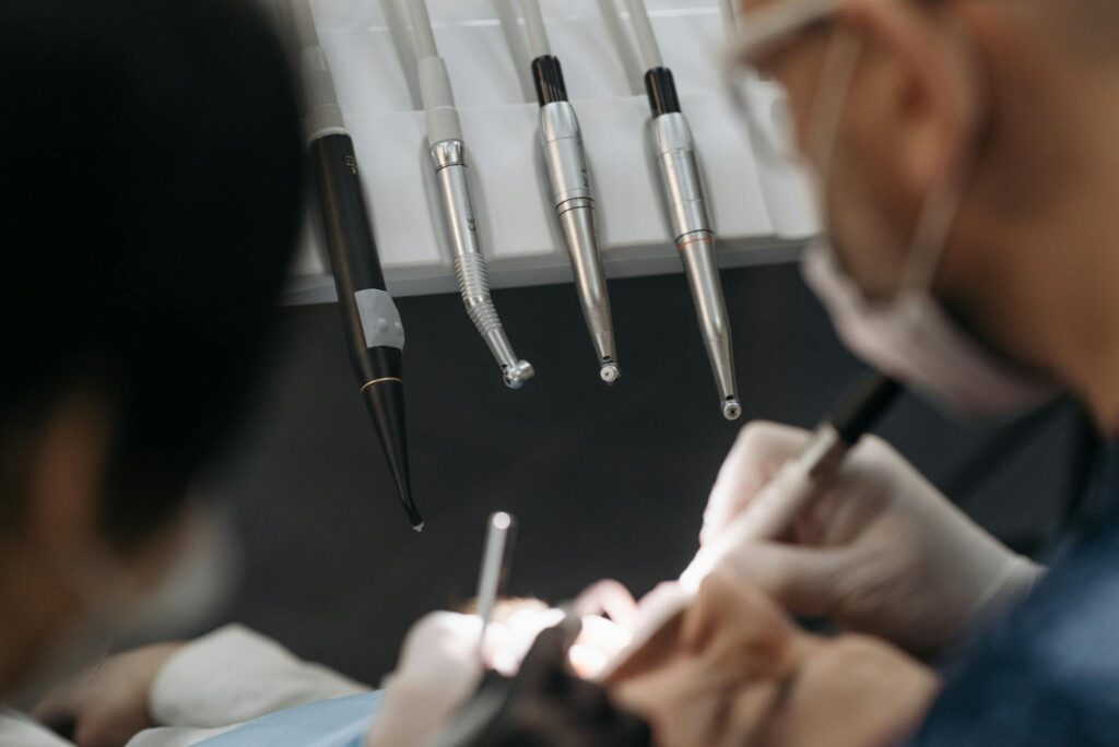 Close-up of dentists working on a patient with specialized dental instruments.