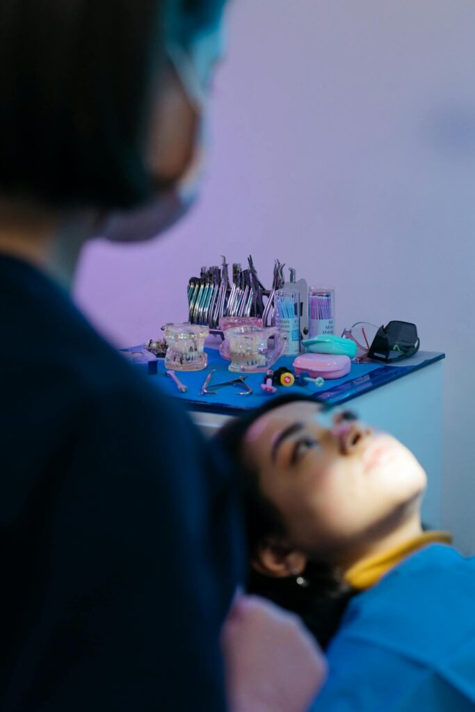 Patient undergoing examination in a modern dental clinic with dental tools visible in background.